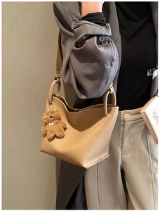 Detail of camel lychee grain leather bucket bag featuring a cute teddy bear charm