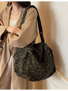 Large dark green leopard print canvas tote bag with side pocket shown on a model