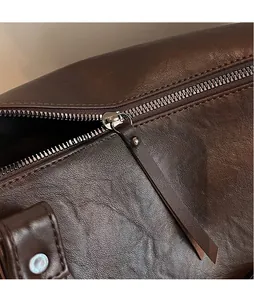 Detail of silver metal zipper and long leather puller on a vintage brown bowling bag