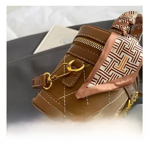 Detail van gouden haken en zijden sjaalhandvat op bruine gewatteerde bucket bag