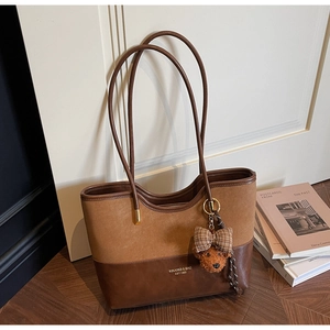 Detail of caramel and coffee tote bag featuring suede texture and plush bear charm