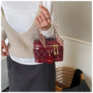 Detail van bordeauxrode vanity case tas met gewatteerd patroon en zijden sjaalgreep