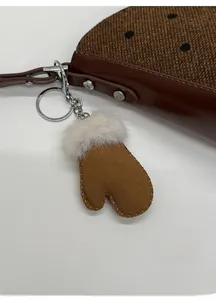 Close-up of a brown glove bag charm with faux fur trim and silver hardware details