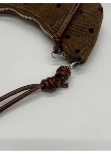 Dettaglio del tessuto a pois marroni con tracolla regolabile in pelle marrone scuro con nodo
