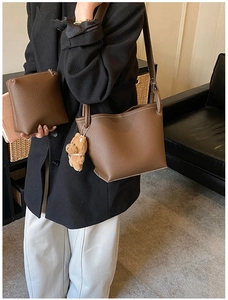 Detail of dark brown pebble leather bucket bag with contrast stitching and bear charm