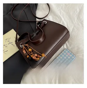 Detail of dark brown leather tote featuring vintage wooden bead charm and metal buckle