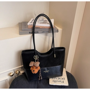 Detail of black patchwork tote bag with matte texture and cute brown bear pendant