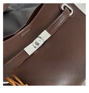 Close-up of silver metal twist lock and smooth dark brown suede leather bag texture