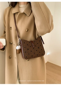 Detail of brown polka dot tweed bag with bow embroidery and white pompom charm