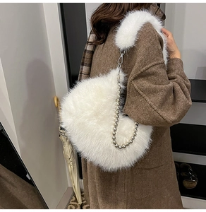 Detail of white plush shoulder bag featuring a metal ball chain and fluffy texture