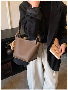 Detail of a brown lychee pattern leather bucket bag with a cute plush bear charm