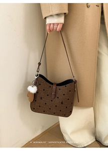 Detail of retro brown polka dot shoulder bag with leather strap and creative glove charm