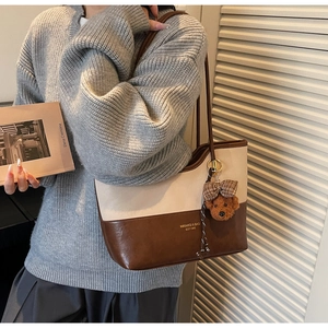 Detail of color-block tote bag with plush bear charm and metallic ring hardware