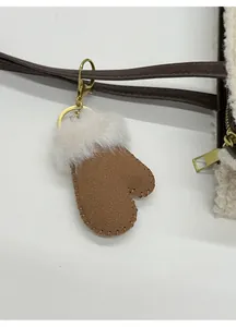 Close-up of glove-shaped plush bag charm with faux suede texture and gold hardware