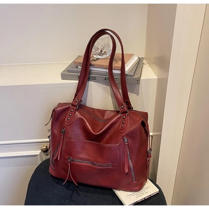 Detailed close-up of a burgundy leather motorcycle bag featuring stylish metal zippers