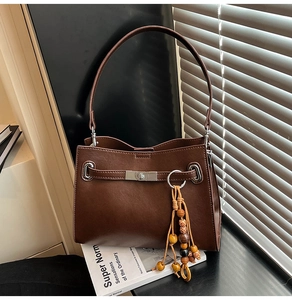 Detail of dark brown leather tote with silver twist lock and vintage wooden bead charm