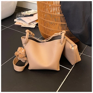 Detail of beige lychee textured bucket bag with teddy bear charm and inner pouch