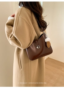 Detail of vintage brown leather bag featuring silver G buckle and white plush pompom