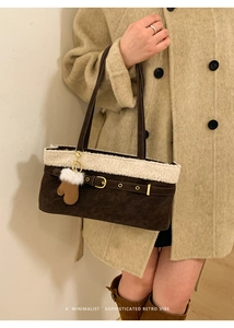 Detail of dark brown suede shoulder bag with cream shearling trim and glove charm