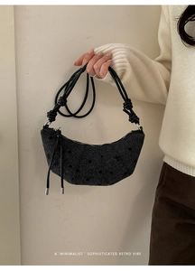 Détail du sac croissant en tweed avec texture tissée et nœuds de corde noire décoratifs