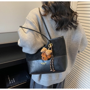 Detail of black patchwork tote bag with suede texture and cute teddy bear charm