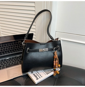 Close-up of black PU leather tote bag with silver twist lock and wooden bead tassel
