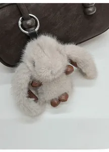 Close-up of a fluffy rabbit bag charm with leather ears on a dark brown handbag