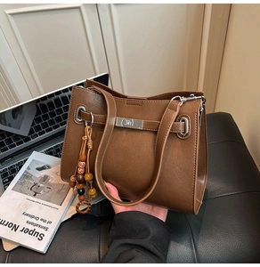 Macro detail of brown vintage leather tote with silver twist lock and beaded charm