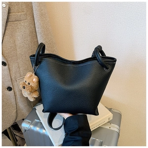 Detail of black lychee grain leather bucket bag with cute dog pendant and silver hardware