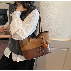 Detail of two-tone brown tote bag with bear charm pendant and MIKAXQI branding