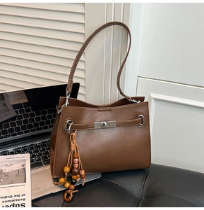 Detailed close-up of brown faux leather tote with metal lock and boho bead charm