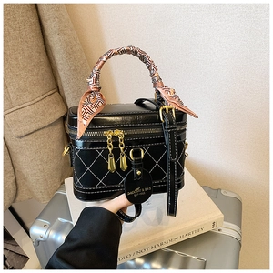 Detail van zwarte gewatteerde box-tas met gouden ketting en handvat met zijden sjaal
