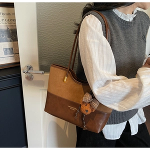 Detail of vintage patchwork tote bag with brand logo, teddy bear charm, and long shoulder strap