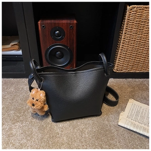 Detail of black litchi grain bucket bag with contrast stitching and puppy charm