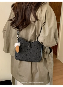Detail of vintage textured crossbody bag with leather trim and decorative fur ball charm