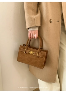 Detalle de bolso retro de ante marrón con relieve de corazón y hebilla dorada