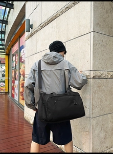 Detail of black nylon travel bag with reinforced handles and multiple zipper pockets
