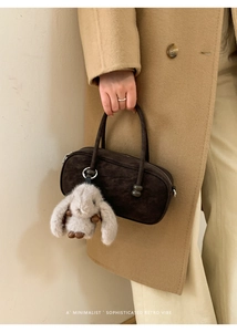 Detailed shot of retro brown suede handbag with a cute plush rabbit pendant charm