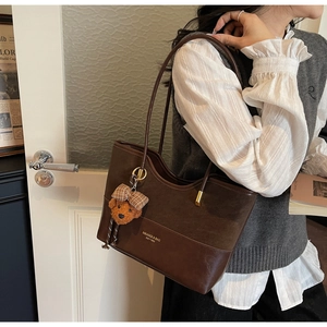 Detail view of vintage dark brown tote bag with patchwork texture and teddy bear charm