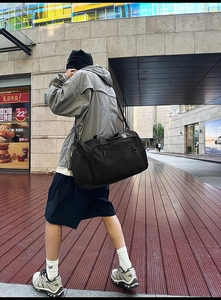 Outdoor street view of a large black travel bag being carried for casual trips