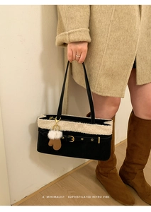 Detail of plush contrast trim on minimalist shoulder bag with glove-shaped charm accessory