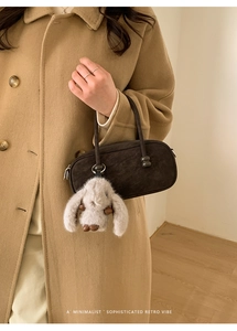 Detail of retro brown suede bowling bag with a cute plush bunny charm and top handle