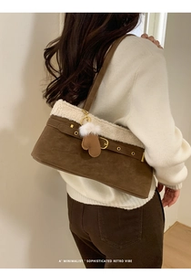 Detail of brown suede shoulder bag with off-white faux fur trim and glove pendant