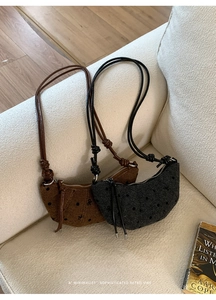 Borse a mezzaluna jacquard a pois marroni e grigie con nappe in pelle su un divano morbido