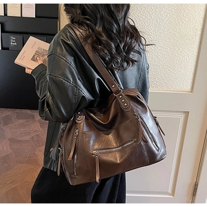Close-up of vintage dark brown tote bag with metal zippers and rivet details