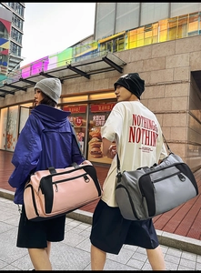 Outdoor street view of models carrying large nylon travel bags in gray and pink colors