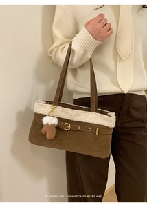 Detail of winter brown suede shoulder bag with plush white trim and glove charm accessory