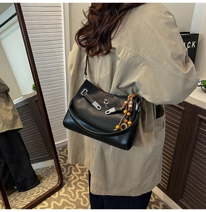 Detail of black matte leather tote bag with silver lock and colorful beaded charm strap