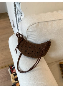 Borsa hobo in tela marrone con pois neri e fiocchi ricamati su un divano bianco
