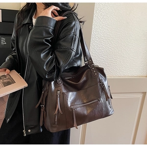 Detail of dark brown faux leather motorcycle bag with multi-pocket zipper and retro design